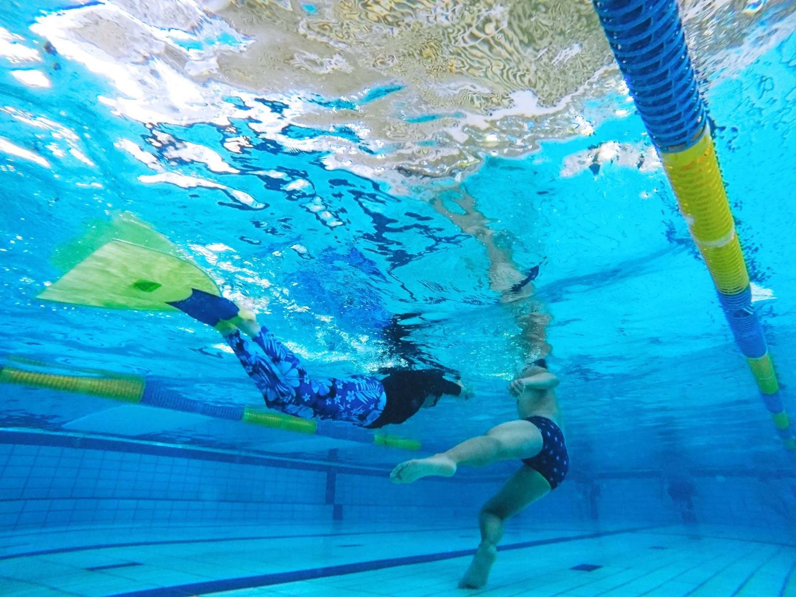 プールの水中でフィンを使って泳ぐレッスンの様子