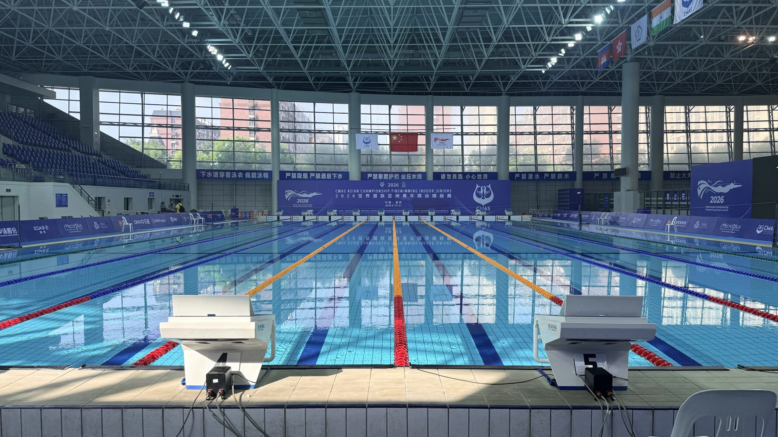 海安体育中心游泳館の競技プール。スタート台側から見た10レーンのプールと、大会ロゴの掲げられた壁面